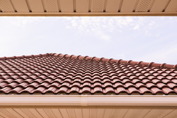 Roof tiles and rain gutter horizontal view against blue sky