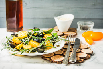 fresh green salad with arugula, yellow tomatoes, olives, grapes