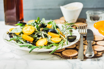 fresh green salad with arugula, yellow tomatoes, olives, grapes