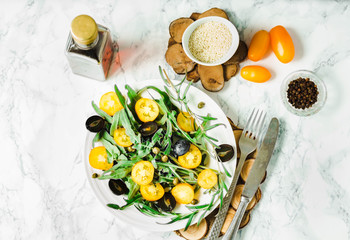 fresh green salad with arugula, yellow tomatoes, olives, grapes