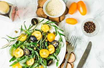 fresh green salad with arugula, yellow tomatoes, olives, grapes