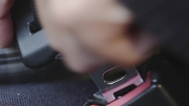 Color footage of a woman unbuckleing  the seat belt.