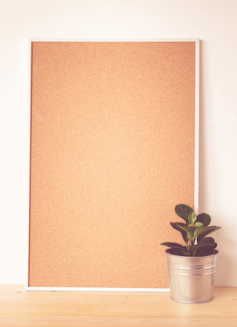 Blank cork board and tree pot on wood table, background, vintage