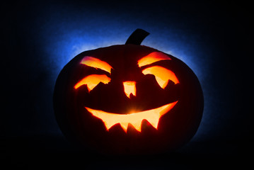 Halloween pumpkin head jack lantern with burning candles on blue  background