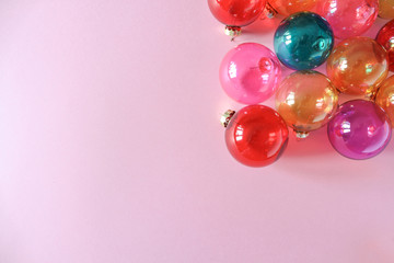 Colourful translucent glass Christmas baubles on pink background. Place for text. Top view