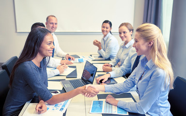 smiling business people shaking hands in office