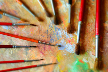 Many paint brushes on a dirty palette. Tilt-shift effect applied.