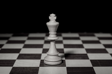 White chess king standing on chessboard alone