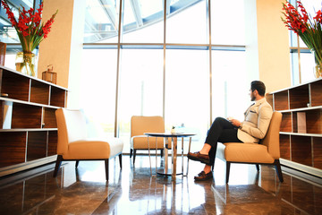 Portrait of handsome successful man drink coffee sitting in coffee shop, business man having breakfast at hotel lobby.