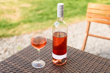 One glass and bottle of red or rose wine in autumn vineyard on wooden wicker table. Harvest time, picnic, fest theme.