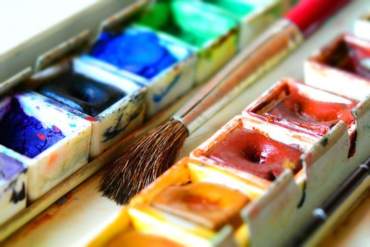 Box of watercolors with a brush. Tilt-shift effect applied.