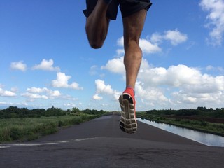 Rear view of man running and jumping down a path on blue sky day