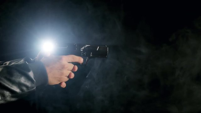 man's hand holding gun dark room back lit smooky scene