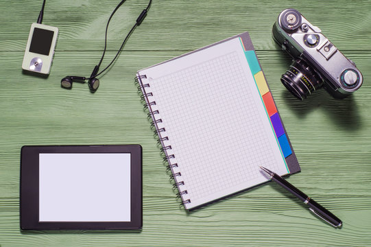 Top view of desktop.  Flat lay of personal stuff tablet pc, camera, notebook and other. Home office, work at home.  Mock up consisting of tablet pc in landscape orientation and blank notebook.