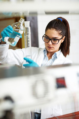 A skilled female lab scientist, deeply engrossed in her work, conducts precise chemical experiments...