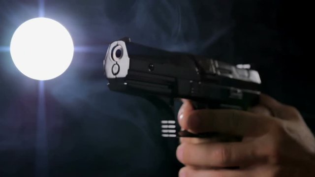 male hand holding gun black smoky background back lit
