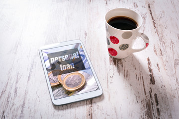 Tablet with personal loan page and black coffee on wooden table. Top view.  
