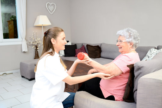 Young Physiotherapist Nurse Helping An Elderly Women Physical Rehabilitation At Home