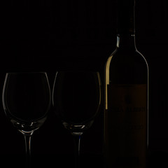 bottle of wine and two glasses on black back