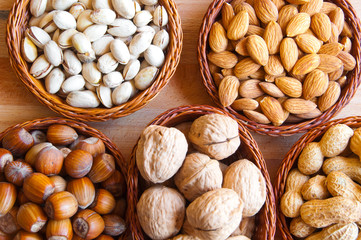 Assorted nuts in bowls: walnut, pistachios, almond, peanut, hazelnut, pine nuts