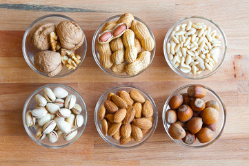 Assorted nuts in bowls: walnut, pistachios, almond, peanut, hazelnut, pine nuts