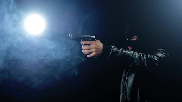 masked criminal gangster holding gun black background