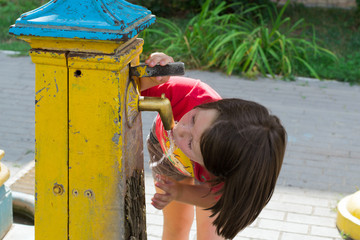 Little girl drinks water from a well