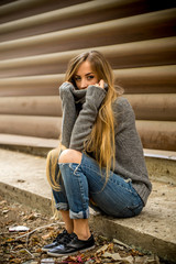 Beautiful girl in a sweater with long hair and red lips on the background of wooden logs