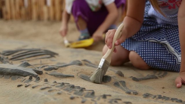 Archaeological excavation of dinosaur bones, children playing in educational game
