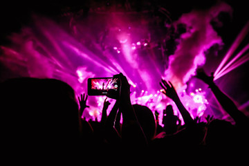 Hand with a smartphone records live music festival, Taking photo of concert stage, live concert,...