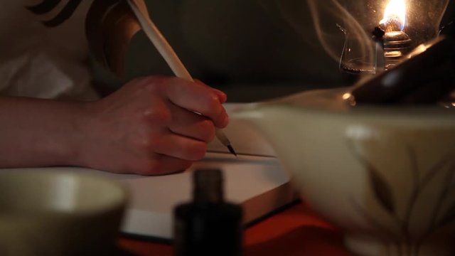 Mano de un hombre joven escribiendo con una pluma sobre un diario en blanco