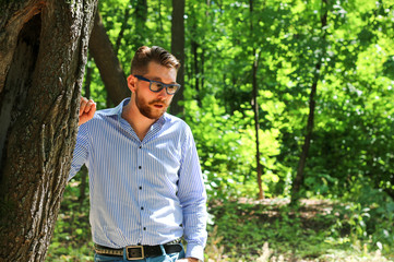 Naklejka na ściany i meble Stylish man in sunglasses stands in the forest