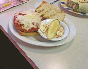 Hot chicken topped with marinara sauce and Parmesan cheese on a ciabatta bun.
