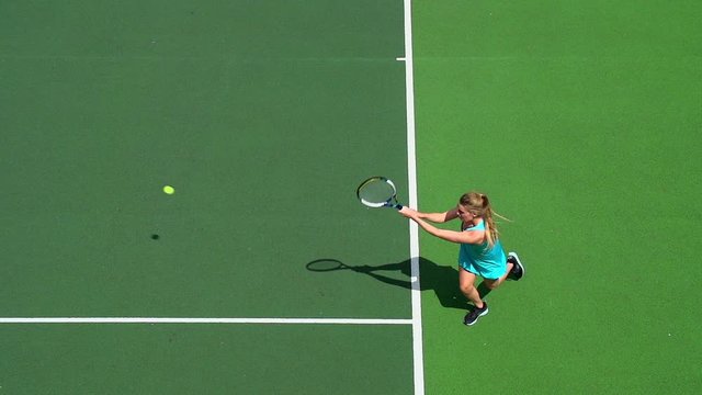 Young female tennis player returns serve.