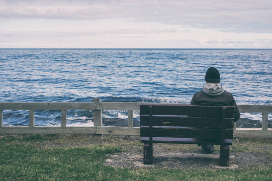 Man sitting on bench overlooking sea
