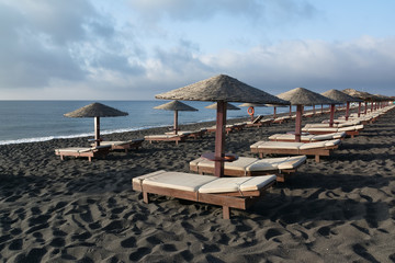 Tanning beds and umbrellas on Perissa beach, Santorini, Greece