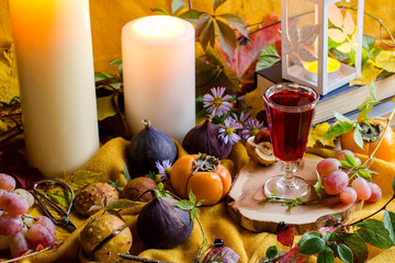 Autumn still life with candles, fruits and books.