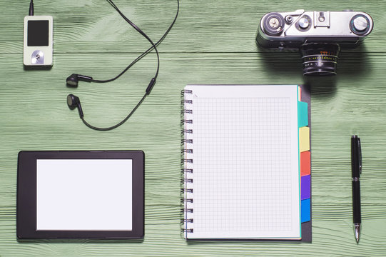 Top view of desktop. Flat lay of personal stuff tablet pc, camera, notebook and other. Home office, work at home. Mock up consisting of tablet pc in landscape orientation and blank notebook.