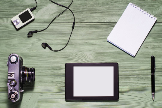 Top view of desktop. Flat lay of personal stuff tablet pc, camera, notebook and other. Home office, work at home. Mock up consisting of tablet pc in landscape orientation and blank notebook.