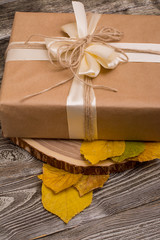 gift box on cutting the tree and yellow leaves on wooden background