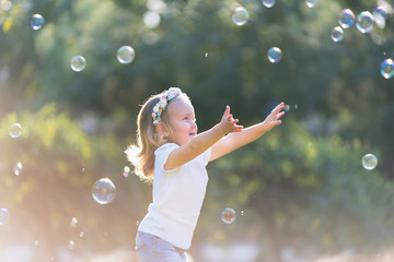 маленькая девочка играет с мыльными пузырями - obrazy, fototapety, plakaty