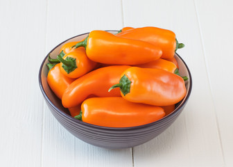 Orange bell pepper in a bowl on a wooden table.