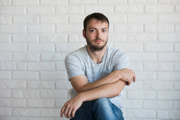 Young man in grey t-shirt, white grunge wall background