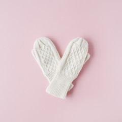beauty white feminine knitted mittens on pink background. flat lay, top view