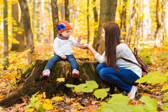 Little girl and her mother playing in the autumn park