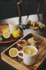 cooking ginger, lemon and honey hot tea in dark rustic interior. Ingredients and cup on wooden background