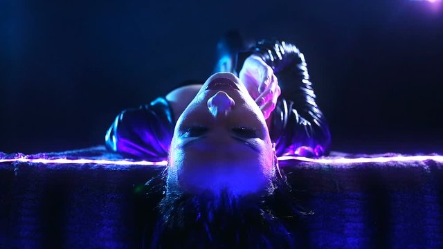 Club Disco Party &ndash; Nightlife. Beautiful Sexy Young Glamorous Woman with Stylish Accessories Dancing and Relaxing in Chill-out. Girl PJ lying on the couch and stroking herself. Neon  illuminated
