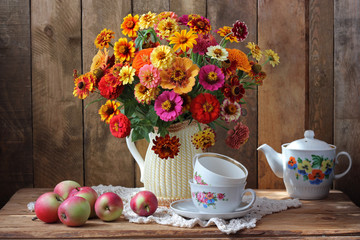 Obraz na płótnie Canvas Still-life with a bouquet of garden flowers and tea utensils.