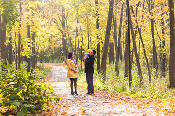 love, parenthood, family, season and people concept - smiling couple with baby in autumn park