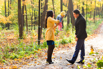 Obraz premium happy young family with their daughter spending time outdoor in the autumn park